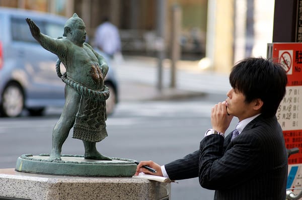 Das Praktische zählt: Ein Salaryman vor einer Statue eines Sumo-Ringers.